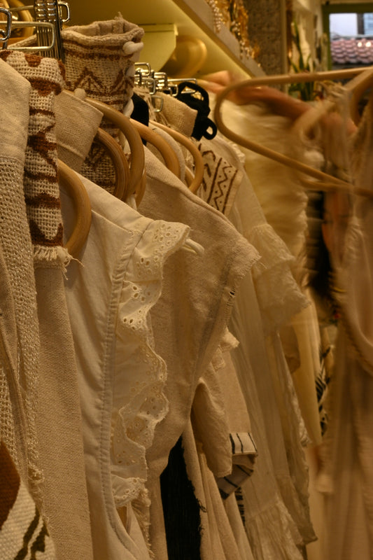 White clothing hangs on a clothing rack.