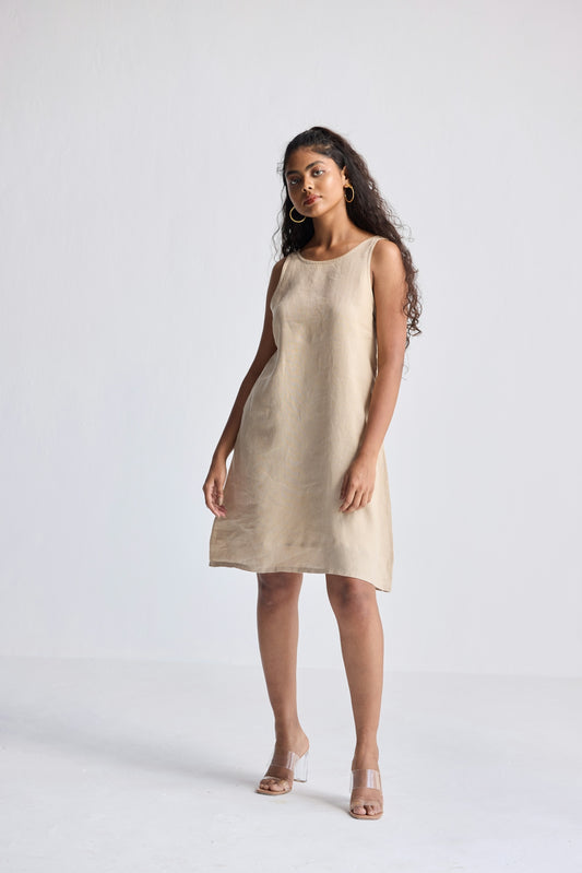 A woman poses in a simple linen dress.